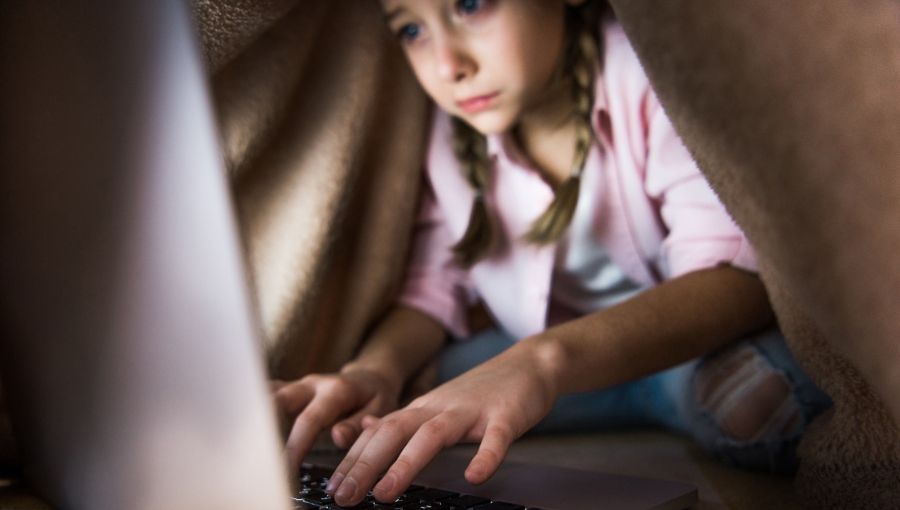 selective focus of frustrated kid covered in blanket typing on laptop keyboard
