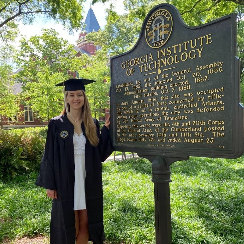 Headshot of Natalie Boutwell in graduation regalia in front of the Georgia Tech incorporation sign.
