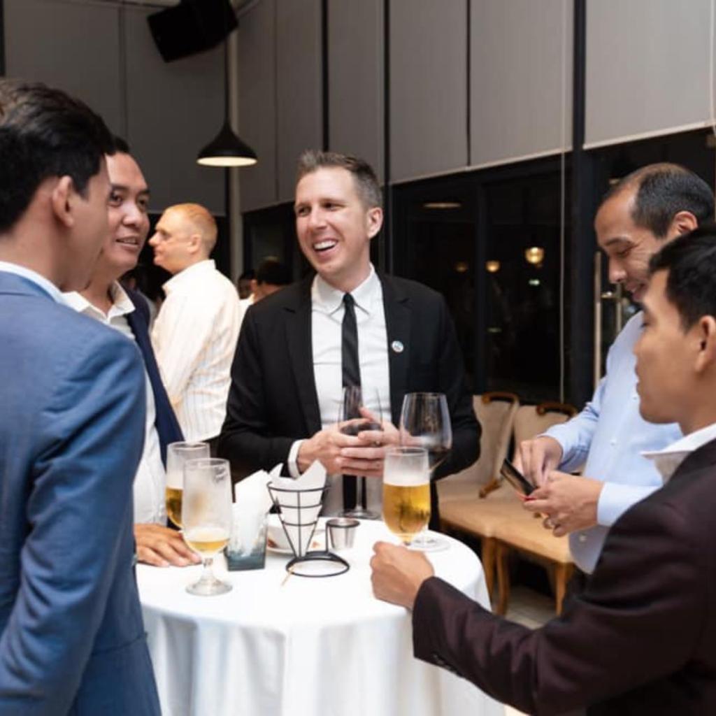 Travis talking to others at a table at a gala-like event